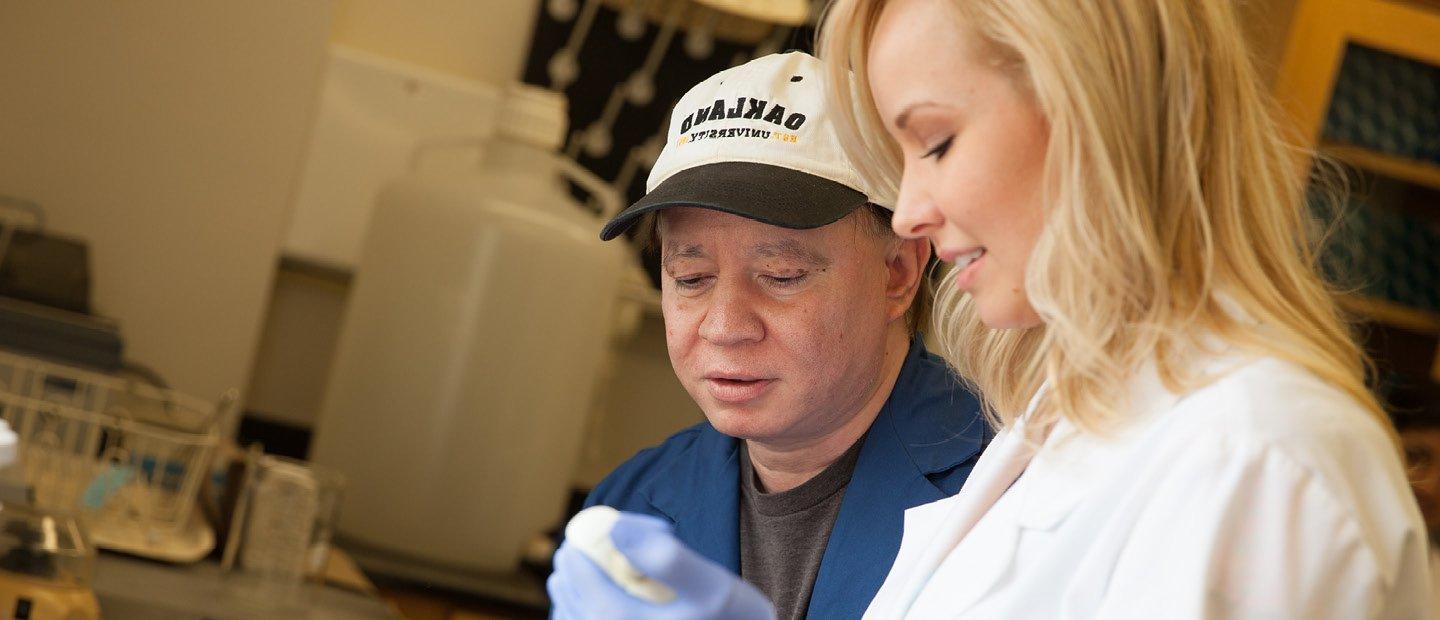 man in a hat and woman in a white coat working in a lab